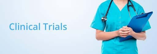 Nurse in blue scrubs holding a clipboard with the words Clinical Trials overlayed beside her